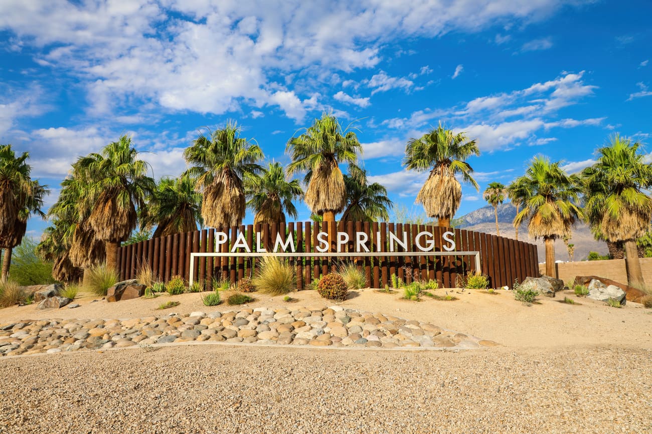 The Palm Springs landmark sign among desert palms in the Coachella Valley